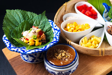 Thai Food concept Fusion Thai snack Miang kham herbal and tuna one bite wrap by perilla leave(shiso) with blend herbals coconut sugar sauce on black background with copy space