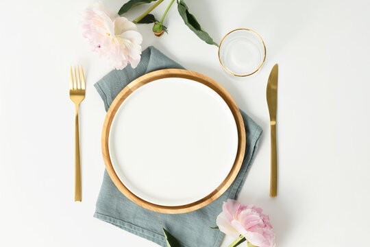 Beautiful table setting with golden cutlery and peony flowers, mock up