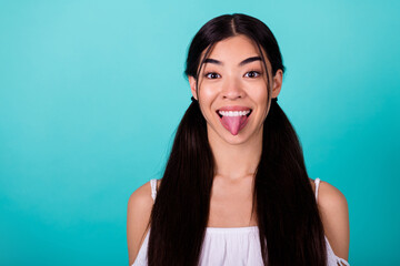 Fototapeta Portrait of cheerful overjoyed vietnamese girl show tongue out have good mood isolated on bright aquamarine color background obraz