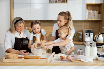 Christmas time happy women and girls preparing homemade dough for baking cooking apple pie cupcakes cookies for family dinner. Everyone helping.