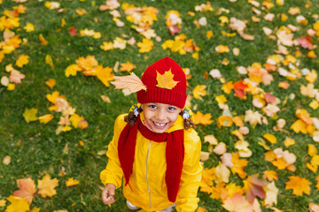 A wide smiling girl made a crown of red and yellow leaves in an autumn park. Queen of Autumn