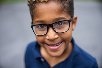 Close up image of a cute african american boy with glasses and a big smile - Powered by Adobe
