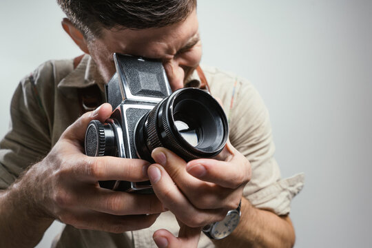 Fashion Photographer with an old film camera in hand while working in studio. .Closeup with focus on the camera.