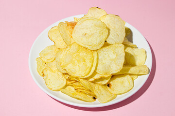 A plate of chips on a pink background. A delicious way to cook potatoes. Delicious fast food