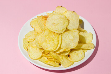 A plate of chips on a pink background. A delicious way to cook potatoes. Delicious fast food