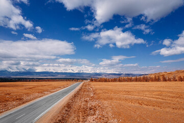 Beautiful landscape road in autumn forest with snow peaks mountains Chuysky tract, Altai Kurai steppe Russia