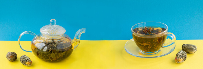 Green tea with lotus flower in the glass teapot and cup on the colored background. Banner. Copy...
