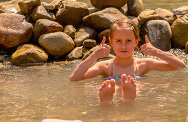 Young beautiful child girl enjoy of water in wild lake.