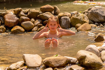 Young beautiful child girl enjoy of water in wild lake. Horizontal image.