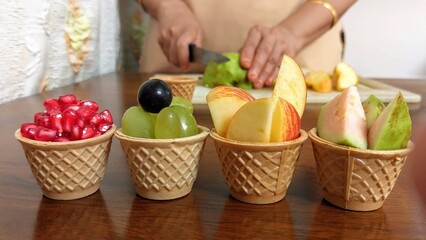 fruits in waffle cup with woman cutting in the background
