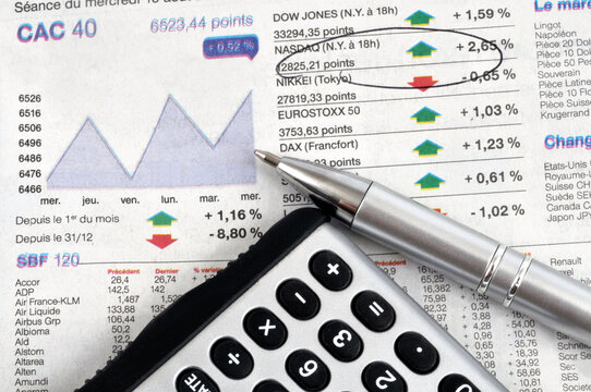 Cotations du CAC 40 et du Dow Jones avec une calculatrice et un stylo en gros plan