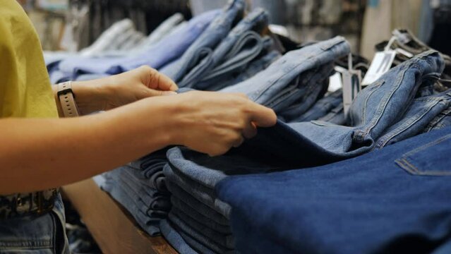 Close-up of a woman looking at jeans in a clothing store.