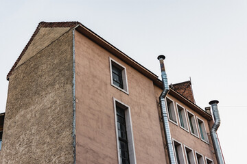 Old abandoned European building with metallic chimneys on the side