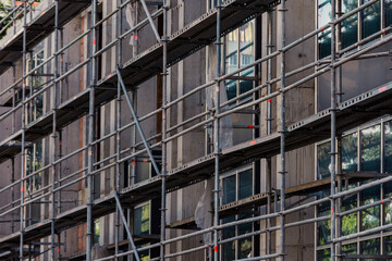 Obraz premium Scaffolding next to a new apartment building under construction. Metallic structure on a construction site
