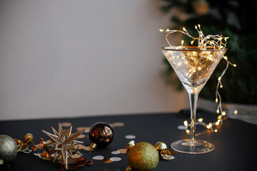Merry Christmas and Happy New Year! Stylish christmas lights in champagne glass, golden confetti...