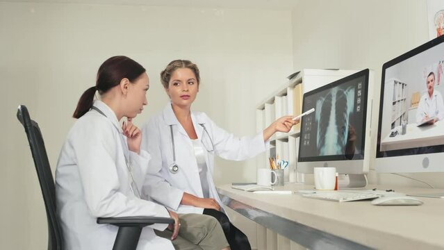Female doctor pointing at chest x ray image on computer and talking to colleague while working together in clinic