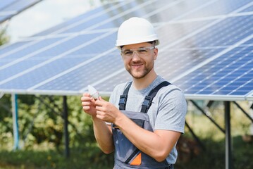 A man holds an Incandescent light bulb in his energy concept, the sun is clean after work and replaces the energy that produces carbon dioxide.