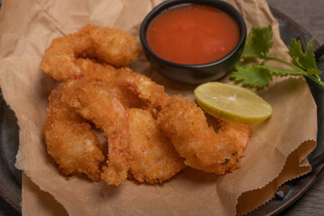Breaded and breaded shrimp with chilli sauce on black background