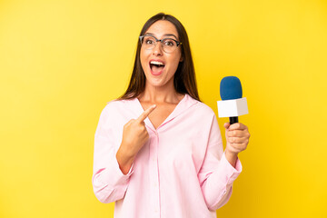 hispanic young adult woman looking excited and surprised pointing to the side. interviewer with a...