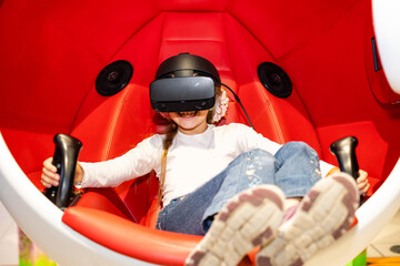 Fototapeta Child with virtual reality headset sitting in a chair booth obraz