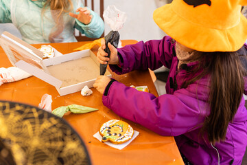 Fototapeta Little girl in Halloween costume plays with gingerbread cookies like a pumpkin obraz