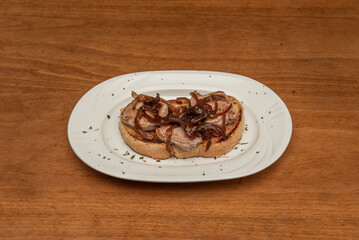 Grilled sirloin toast and caramelized onions sprinkled with dried parsley on a white plate