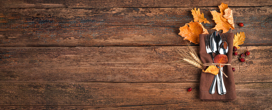 Napkin, cutlery and autumn leaves on a wooden background with space to copy. The concept of Thanksgiving, Halloween