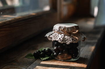 fresh black currant berries in a jar on a wooden windowsill