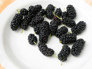 ripe dark mulberry berries on a white plate