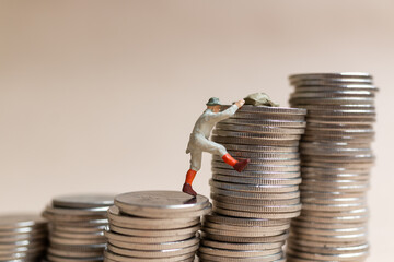 Miniature people Mountain climber ascending the coin stack
