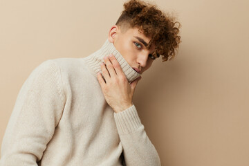 a close portrait of a handsome, attractive man with curly hair, in a light turtleneck pulled over his face, pulling it off with his hand