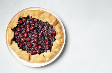 Fresh cherry and blueberry galette with coconut on white plate, top view, copy space, white background. Homemade rustic dessert - american pie or tart or cake or french galette