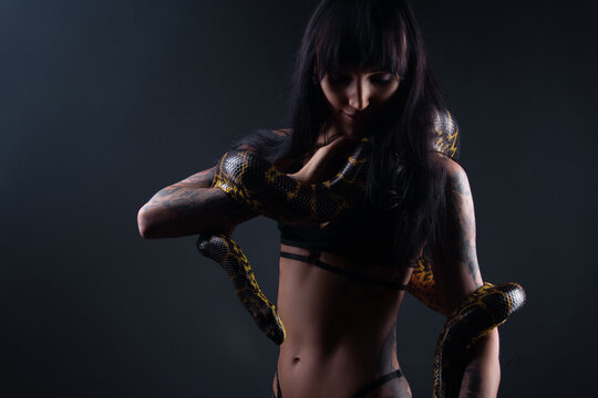 Photo of brunette woman with snake in shadows