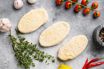 Uncooked Raw breaded patty cutlets, on gray stone table background, top view flat lay