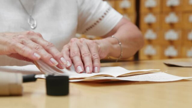 4K. An elderly woman writes a letter and puts it in an envelope