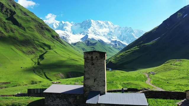 Aerial view of green pasture against highest georgian mountain Shkhara near Ushguli in Georgia.