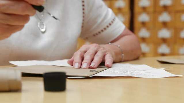 4K. An elderly woman writes a letter in the library