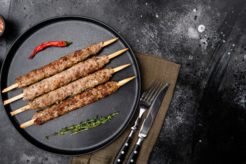 Kofta or lula beef and lamb meat kebabs skewers, on plate, on black dark stone table background,...