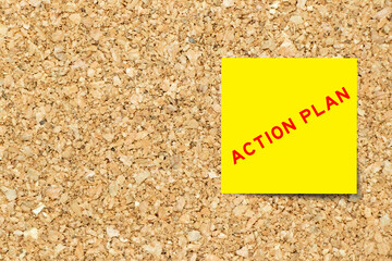 Yellow note paper with word action plan on cork board background with copy space