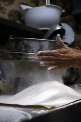 repostera tamizando harina para elaborar pan