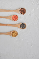 Different or various types of dry beans or dried legumes in wooden spoon on white background. Whole grains, healthy food and diet concept. Top view. Flat lay