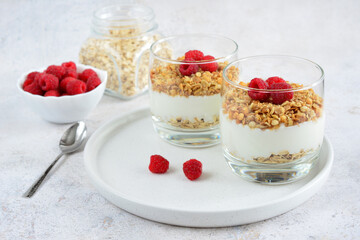 muesli with yoghurt and raspberry in drinking glasses on white tray, close-up