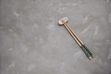Wooden chopsticks and chopstick rest on a gray background. Top view. Copy space