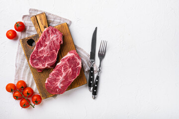 Top blade steak of marbled beef with pepper, on white stone table background, top view flat lay,...