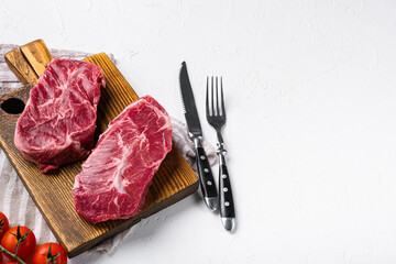 Marbled beef steak, top blade meat steak, on white stone table background, with copy space for text