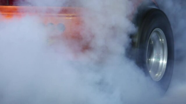 Car wheel spinning wheel and smoking, Race car burning tire for warm up tire before competition, Racing car burns rubber preparation for race on speed track.