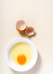 Raw eggs and egg shell in a glass bowl on the table. Top View. Broken White Background.