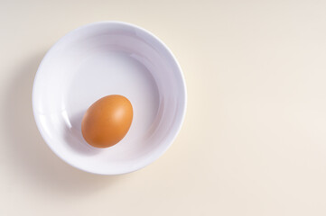Whole raw egg in white bowl. Top view. Broken White Background.