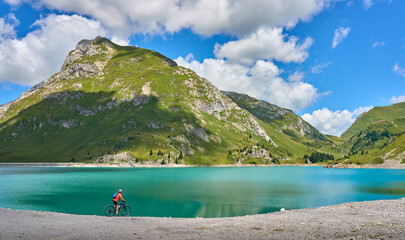 active senior woman, riding her electric mountain bike at Spuller Lake in the Arlberg area near the...