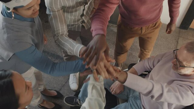 Top view of diverse people putting hands together in circle as team